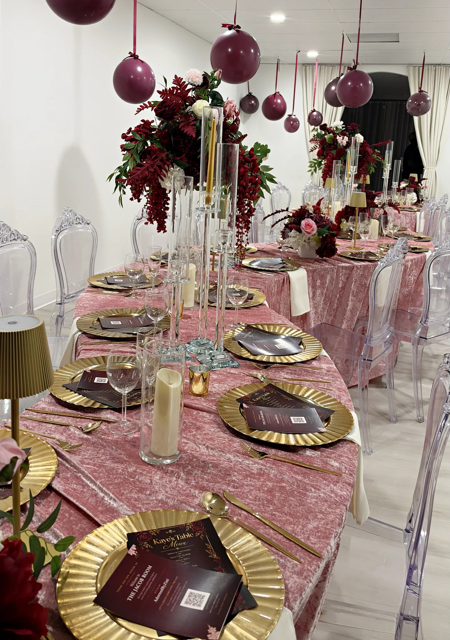 Gold place settings and floral centerpieces on curved blush tables in The Jacob.