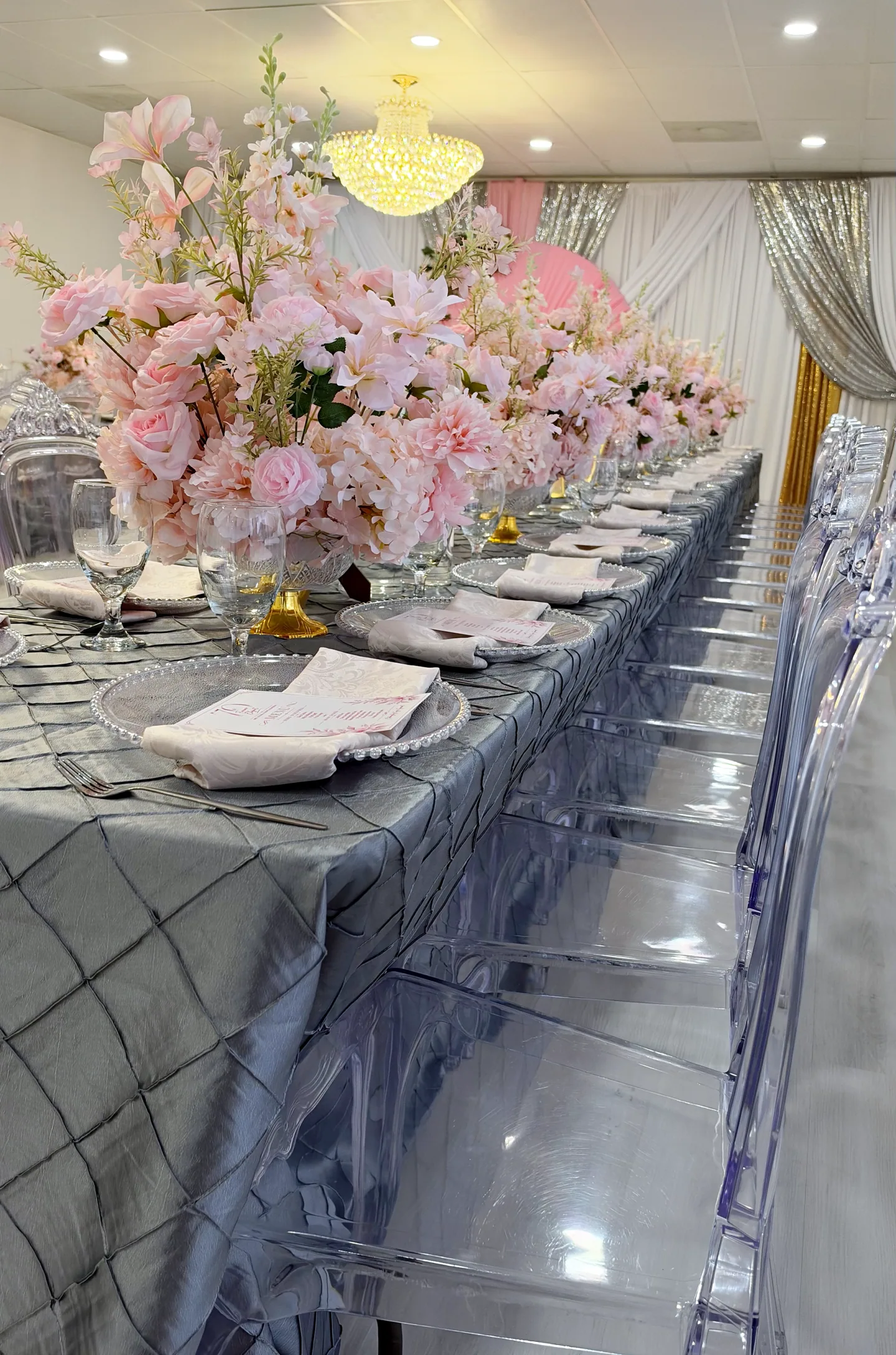 Pink floral arrangements and silver place settings along a dining table in The Victoria.