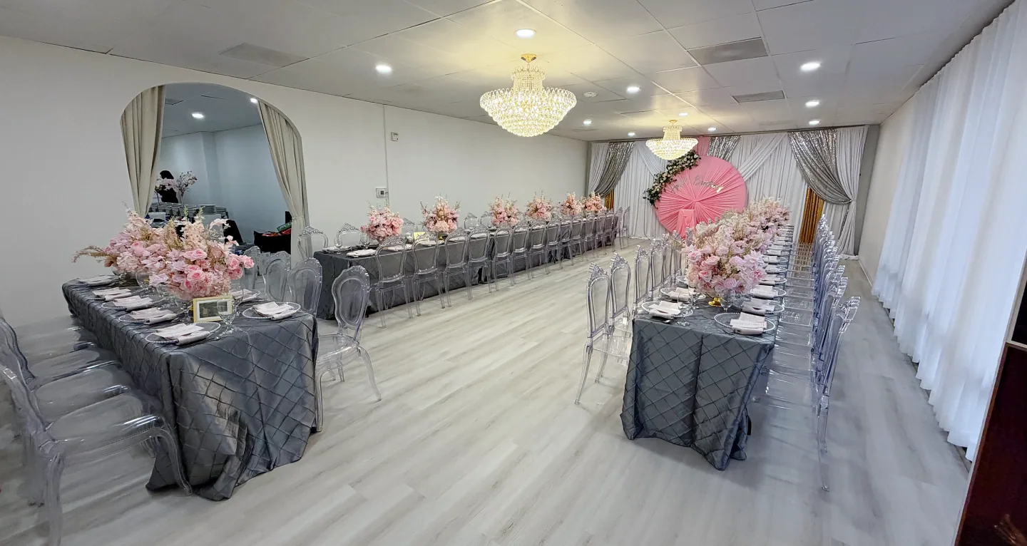 A side view across The Victoria with long floral dining tables, chandeliers, and draped windows.