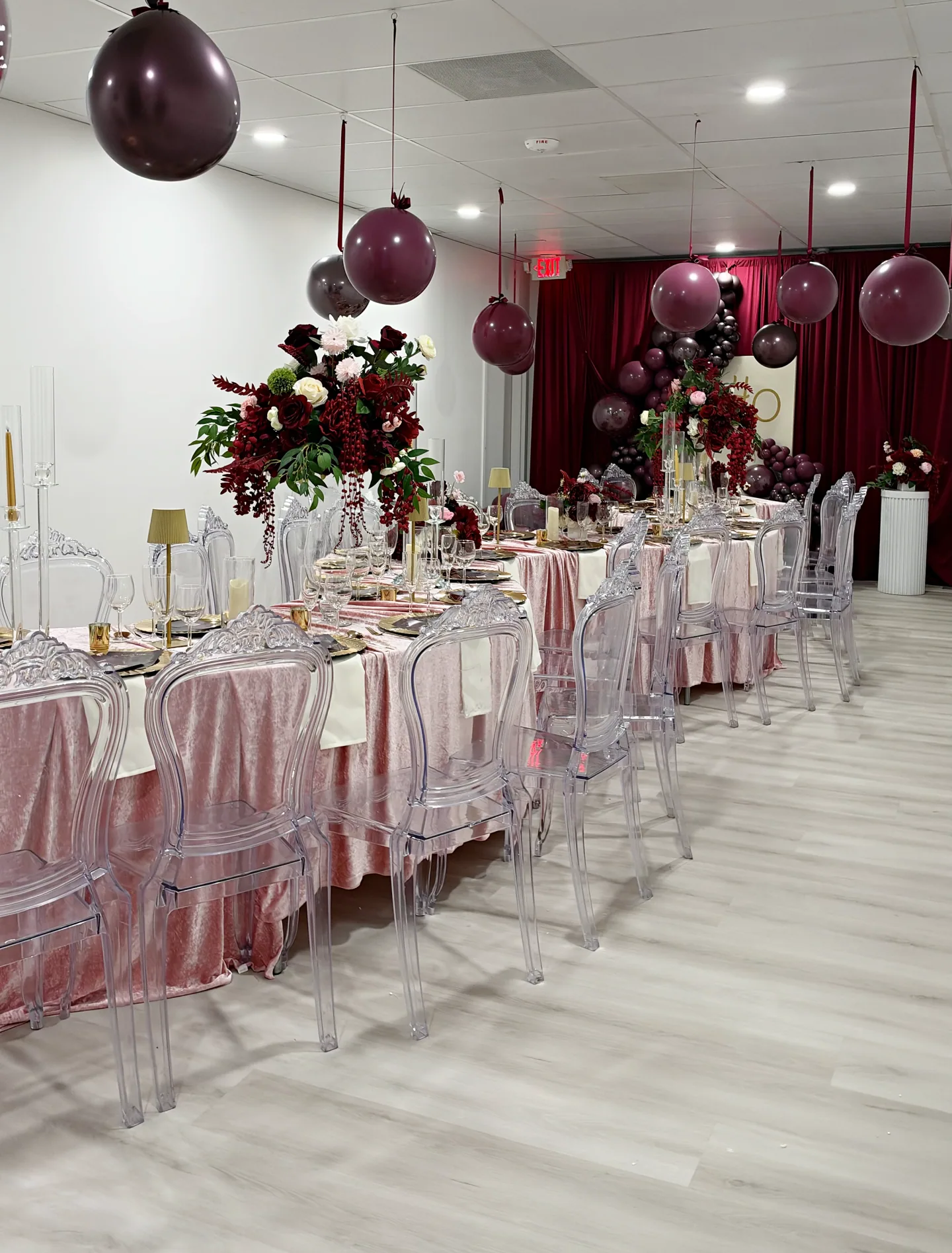Blush dining tables, clear chairs, and burgundy balloons in The Jacob.