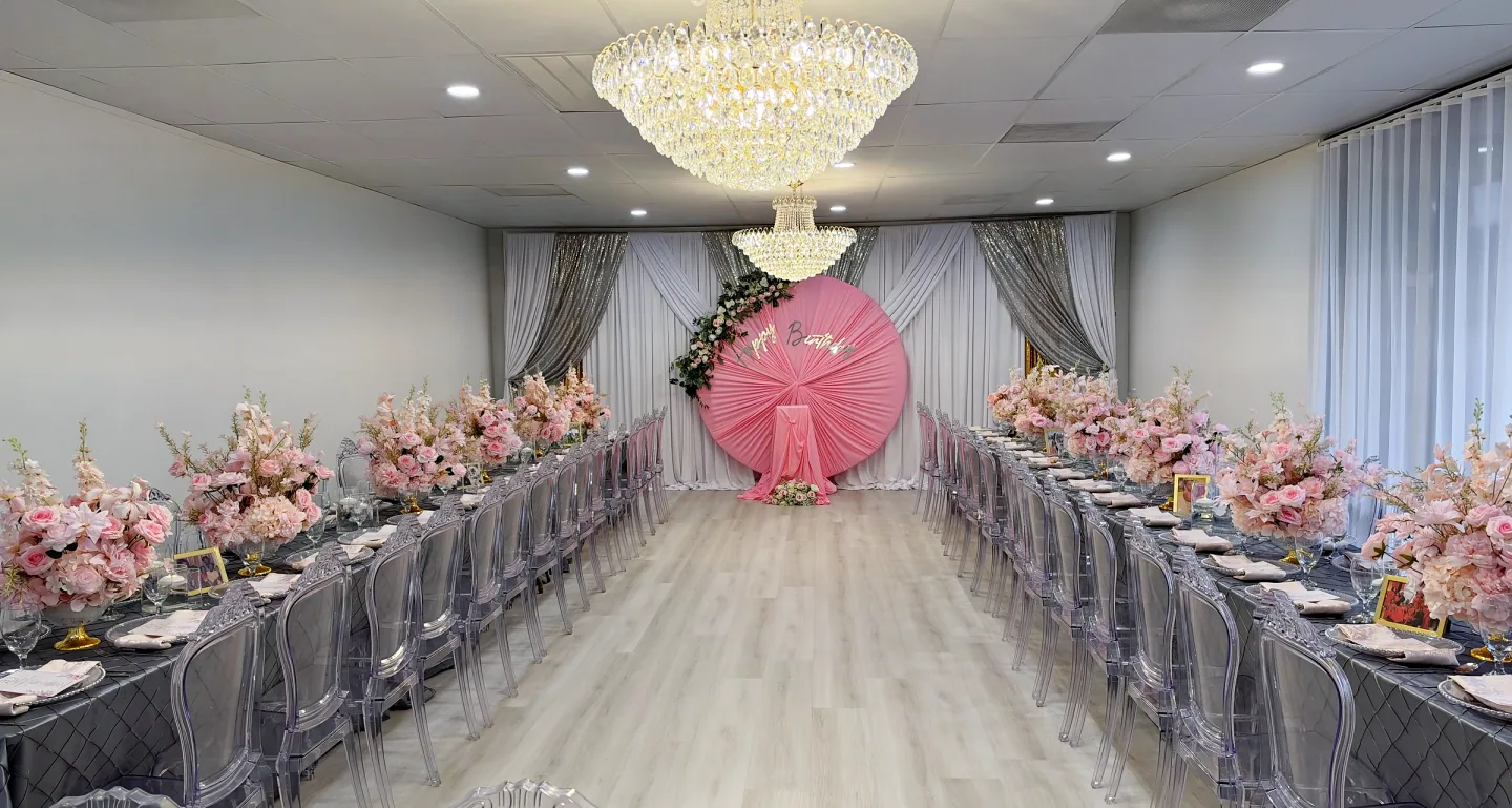 Long floral dining tables and chandeliers framing a pink birthday backdrop in The Victoria.
