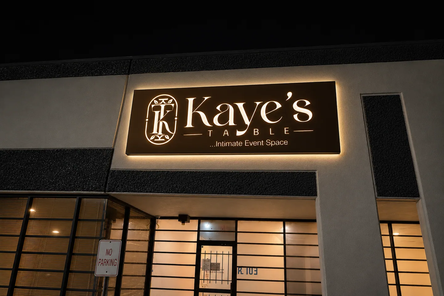 The illuminated Kaye’s Table exterior sign at night.